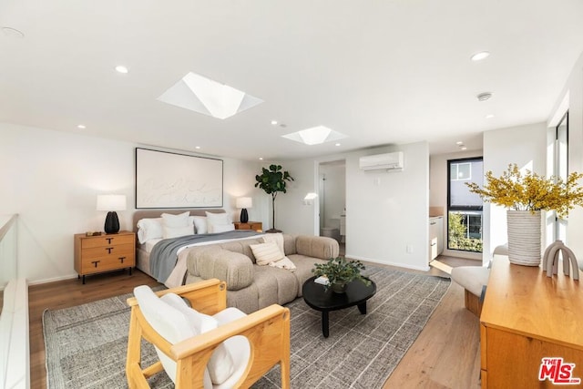 bedroom with light hardwood / wood-style flooring, a wall mounted AC, and a skylight