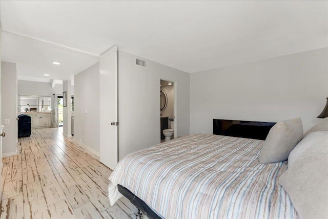 bedroom with light wood-type flooring and connected bathroom