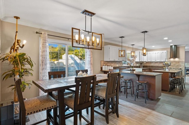 dining space with an inviting chandelier, ornamental molding, and light hardwood / wood-style floors