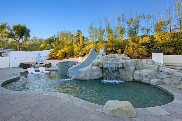 view of swimming pool featuring pool water feature and a patio