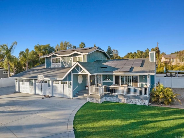 view of front of property with solar panels, a porch, a front lawn, and a garage