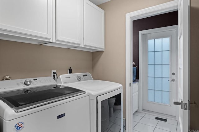 laundry room with washing machine and dryer, light tile patterned floors, and cabinets