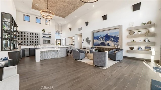 living room featuring a raised ceiling, a towering ceiling, and an inviting chandelier