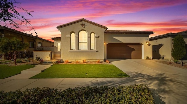 mediterranean / spanish-style house featuring a garage and a lawn