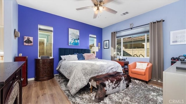 bedroom with ceiling fan, multiple windows, and hardwood / wood-style flooring