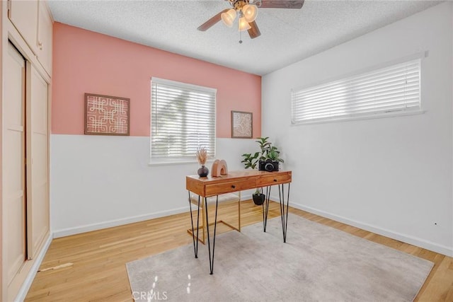 home office featuring a textured ceiling, ceiling fan, and light hardwood / wood-style floors