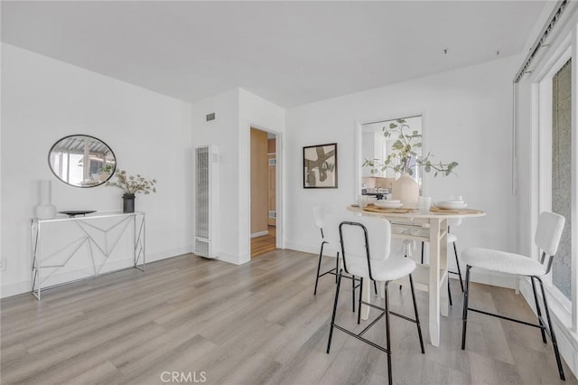 dining space with light hardwood / wood-style floors and a healthy amount of sunlight