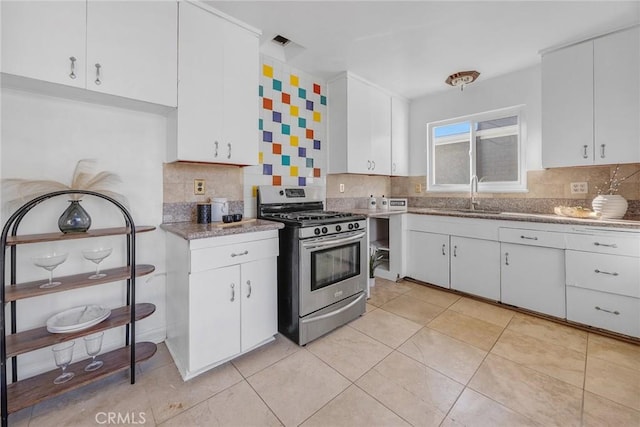 kitchen featuring white cabinets, backsplash, gas stove, and sink