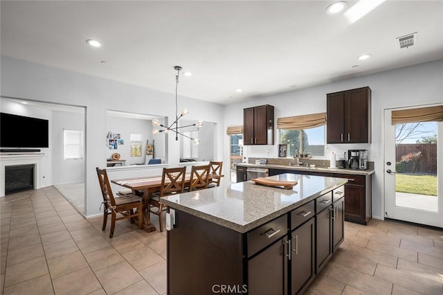 kitchen featuring pendant lighting, a center island, an inviting chandelier, sink, and dark brown cabinets