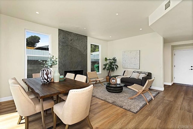 dining room with a premium fireplace, a healthy amount of sunlight, and hardwood / wood-style flooring