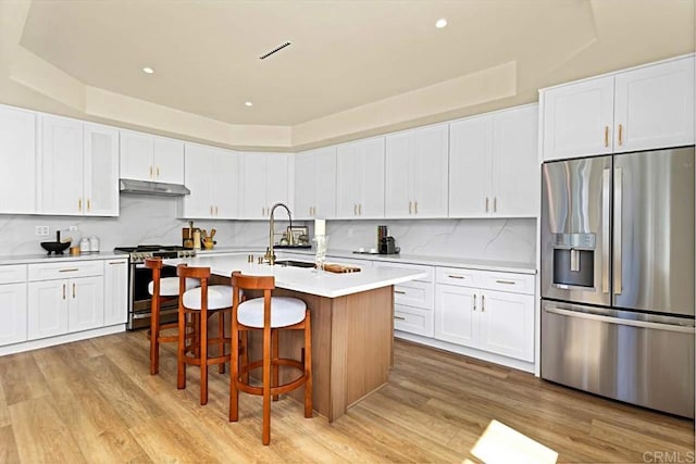 kitchen with white cabinets, appliances with stainless steel finishes, and light hardwood / wood-style flooring