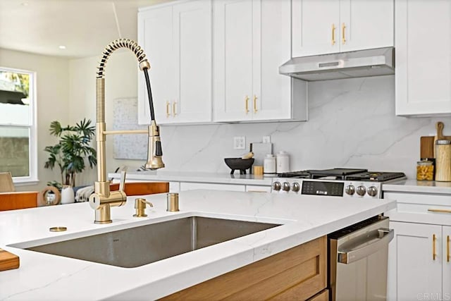 kitchen featuring light stone countertops, white cabinetry, and sink