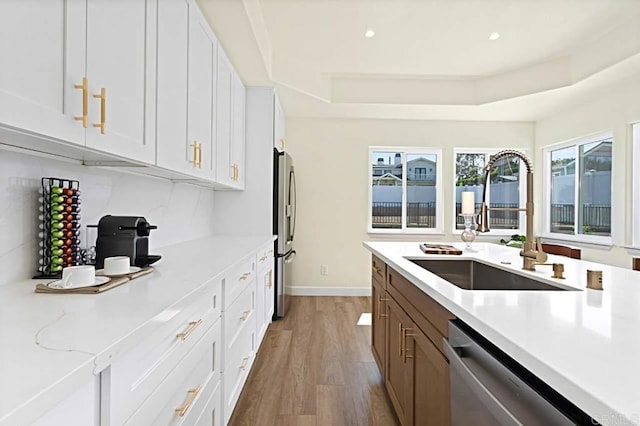 kitchen featuring a raised ceiling, white cabinetry, sink, and appliances with stainless steel finishes