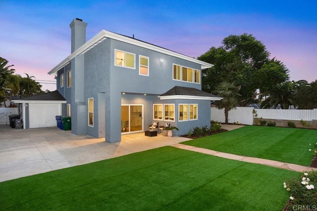 back house at dusk with a yard and a patio