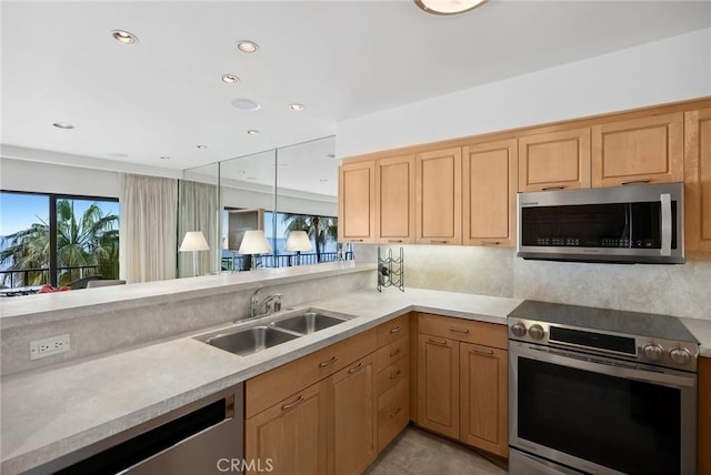 kitchen with appliances with stainless steel finishes, light countertops, a sink, and recessed lighting