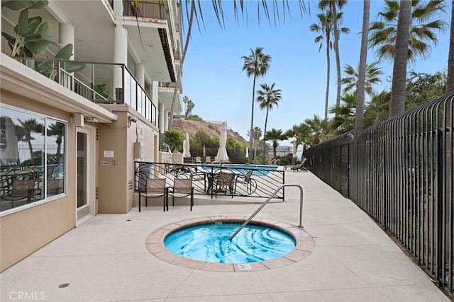 view of swimming pool featuring fence, a community hot tub, and a patio