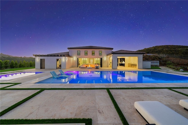 pool at dusk featuring a patio area and a jacuzzi