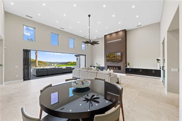 dining room with ceiling fan and a towering ceiling