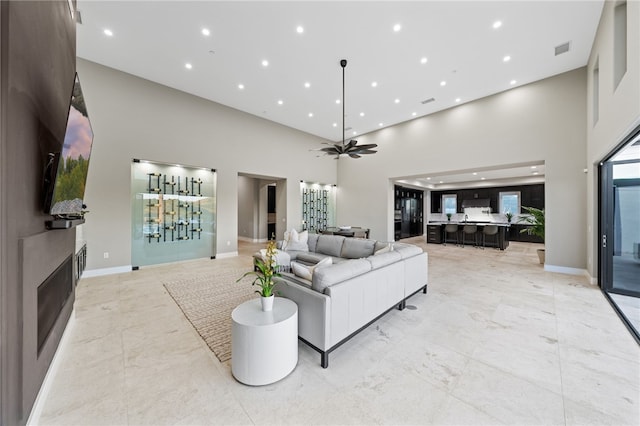 living room with ceiling fan and a high ceiling