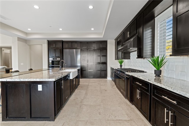 kitchen featuring light stone countertops, sink, tasteful backsplash, a spacious island, and high end appliances