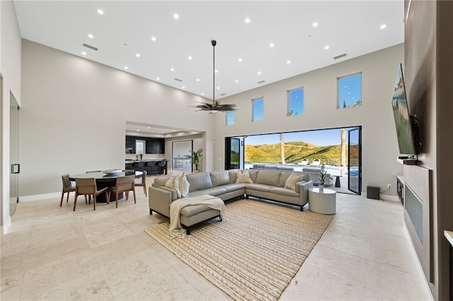 living room featuring ceiling fan and a towering ceiling