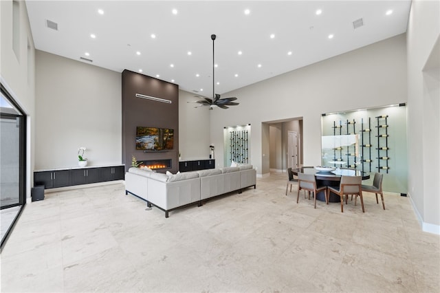 living room featuring a towering ceiling, a large fireplace, and ceiling fan