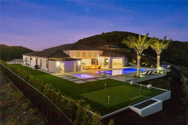 back house at dusk featuring a fenced in pool, an outdoor living space with a fire pit, and a patio