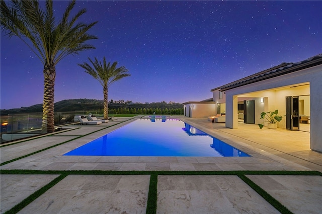 pool at dusk with a patio area