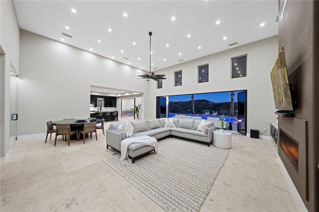 living room featuring ceiling fan and a high ceiling