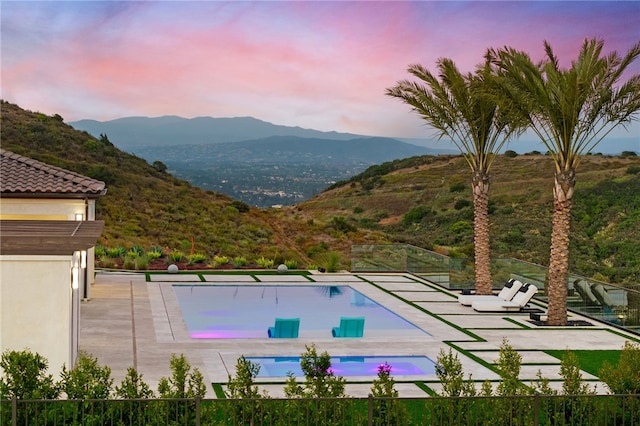 pool at dusk with a mountain view and a patio area