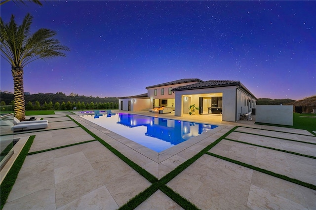 pool at dusk featuring a patio area