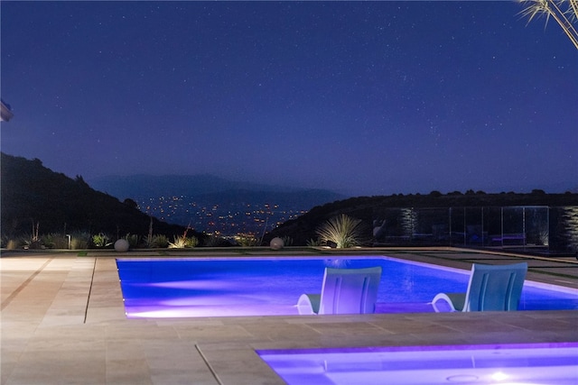 pool at night with a patio area