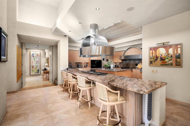 kitchen with island range hood, kitchen peninsula, a breakfast bar area, backsplash, and light parquet flooring