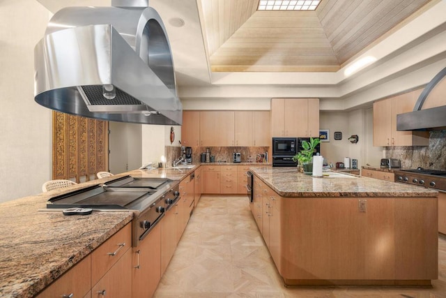 kitchen featuring ventilation hood, a kitchen island, light brown cabinetry, and light stone counters