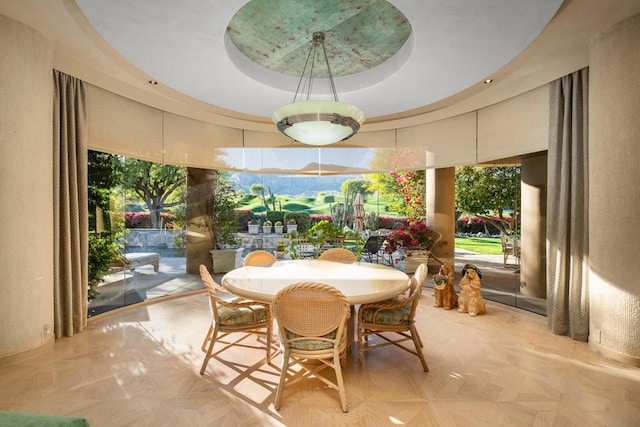 dining area featuring a raised ceiling and light parquet flooring