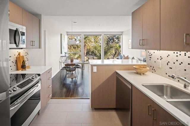 kitchen with decorative backsplash, appliances with stainless steel finishes, decorative light fixtures, and sink