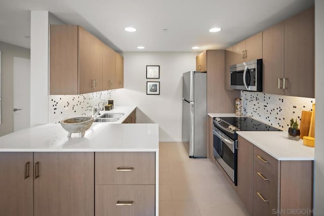 kitchen featuring sink, light brown cabinets, tasteful backsplash, kitchen peninsula, and appliances with stainless steel finishes