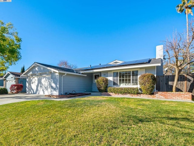 ranch-style house with a front yard, a garage, and solar panels