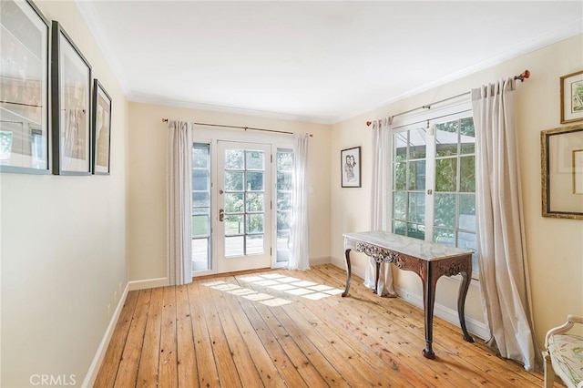 doorway to outside with a healthy amount of sunlight, ornamental molding, and light hardwood / wood-style flooring