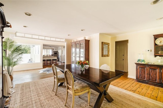 dining area with light hardwood / wood-style floors and ornamental molding