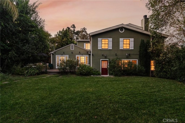 back house at dusk with a lawn