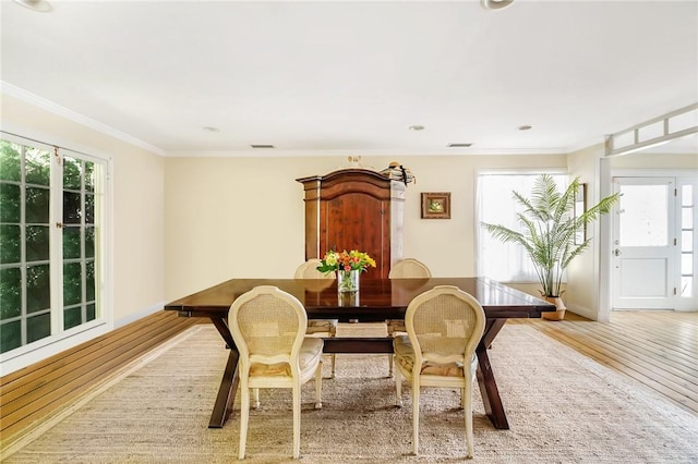 dining space with light hardwood / wood-style flooring and ornamental molding