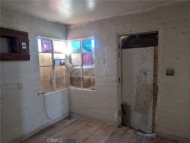 interior space featuring brick wall and wood-type flooring