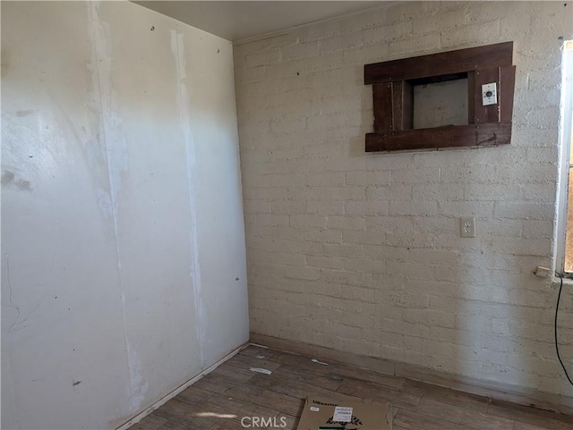 spare room with hardwood / wood-style flooring and brick wall