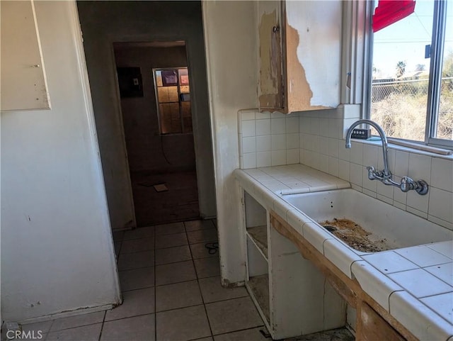 kitchen with sink, decorative backsplash, tile countertops, and light tile patterned flooring