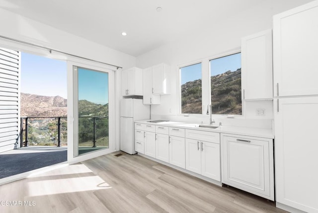 kitchen featuring a mountain view, white cabinets, white refrigerator, sink, and light hardwood / wood-style floors