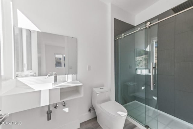 bathroom with toilet, a shower with shower door, and wood-type flooring