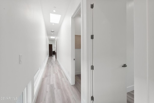 hallway featuring a skylight and light hardwood / wood-style flooring