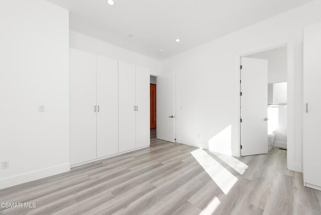 unfurnished bedroom featuring light wood-type flooring and connected bathroom