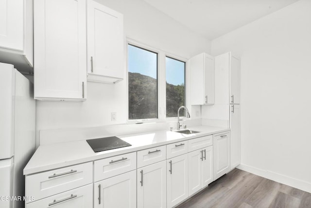 kitchen featuring white cabinets, light wood-type flooring, white fridge, and sink